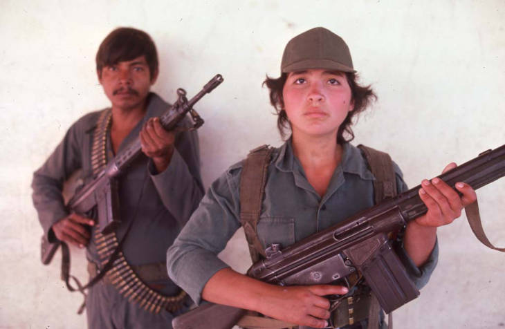 Guerrilleros with rifles standing in front of white wall