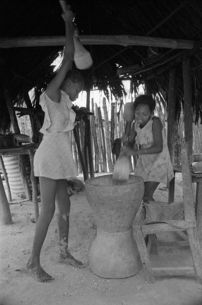 Girls pounding grain in a mortar
