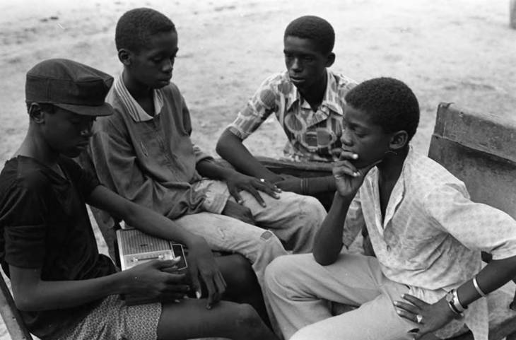 Four boys gathered together listening to the radio