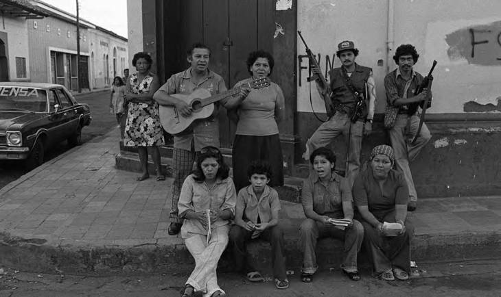 Group of people sing on a street corner next to Sandinistas