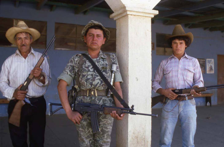 An armed soldier and two members of the civil defense