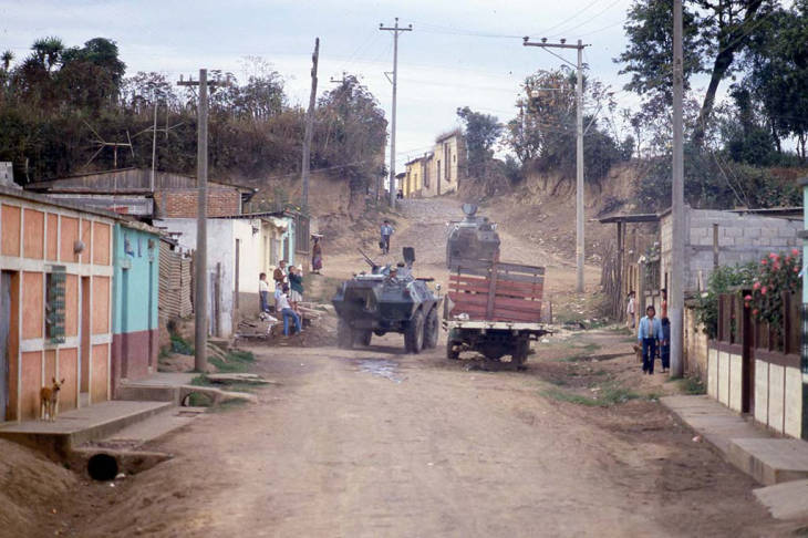 Two Cadillac Gage Commando vehicles patrol a hamlet