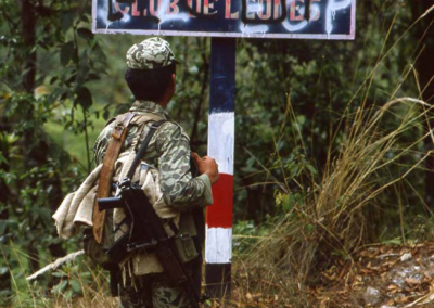 Armed soldier looks at anti-guerrilla slogans on a street sign