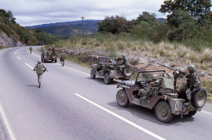 Armed soldiers in jeeps patrol the roads