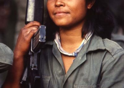 A military woman is wearing her military uniform and holding a rifle in her arms