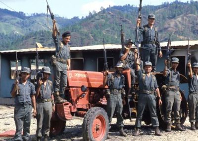 A group of men standing near and on a tractor are holding up their rifles.